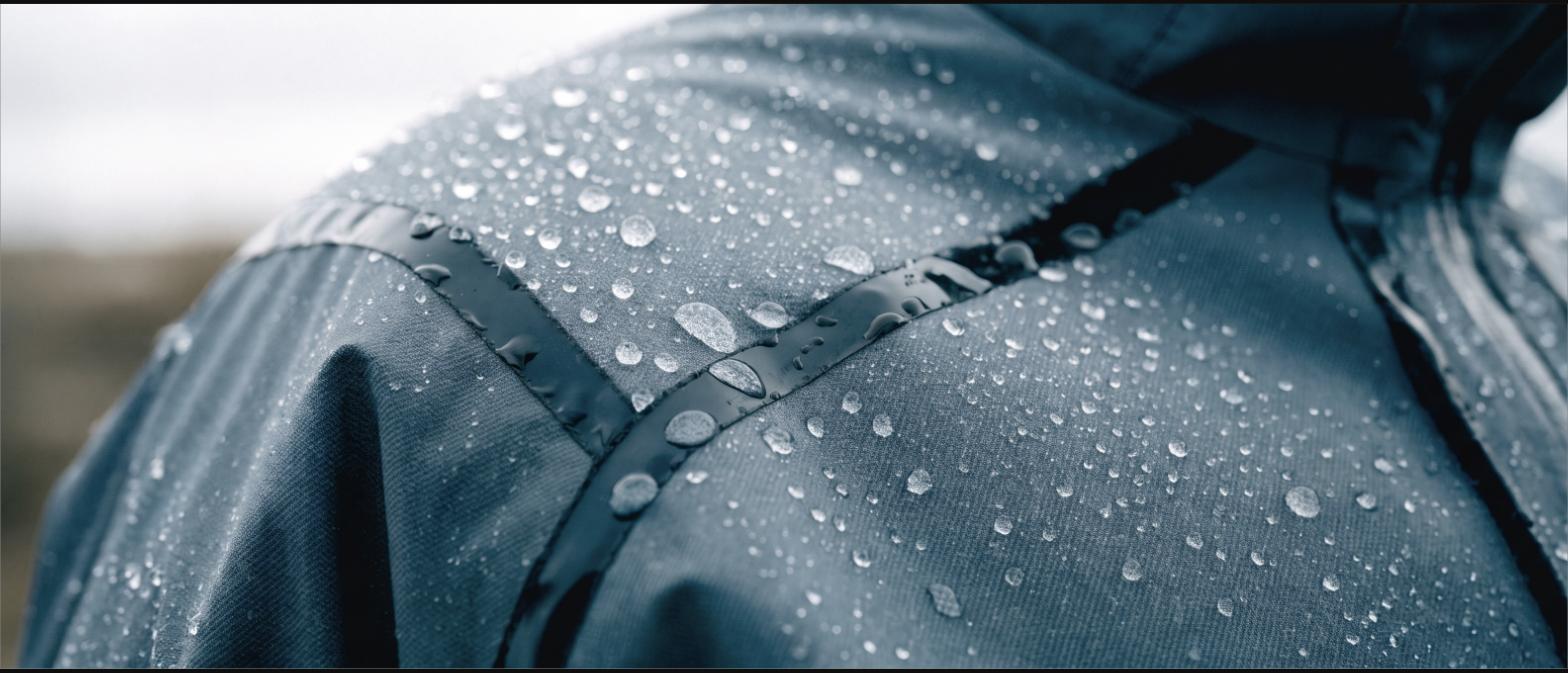 Close-up of a waterproof shell with taped seams and water beading on the fabric
